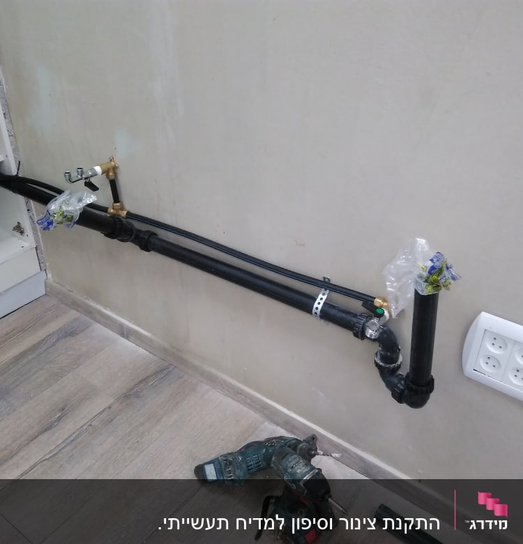 צינורות שחורים מותקנים על קיר עם ברזים